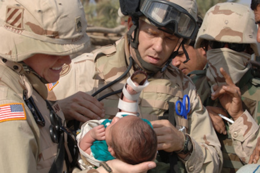 Capt. Ronald Leach (center), U.S. Army, examines a local child with the help of Sgt. Georgina Kirkland (left) during a community health outreach program services mission conducted in Al Qudria, Iraq, on Nov. 22, 2005. Soldiers of the 550th Area Support Medical Company and the 490th Civil Affairs Battalion, 3rd Brigade Combat Team are bringing medical treatment to residents of Al Qudria. 