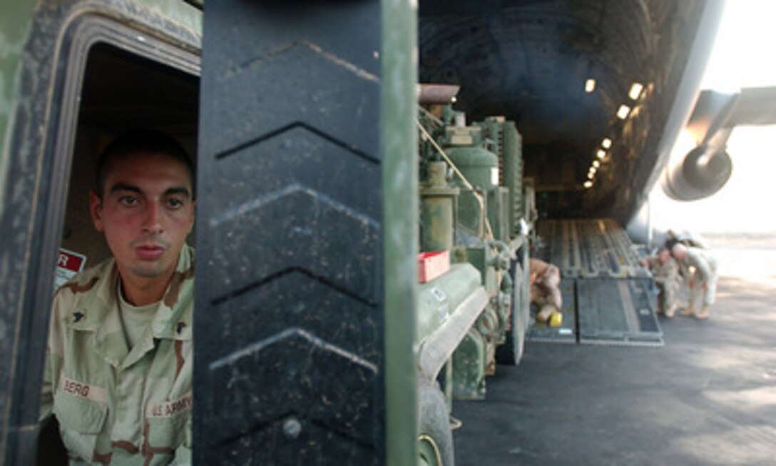 Army Sgt. Weston Berg watches flight crew members in his mirror as he steers an LP-12 well rig into a C-17 Globemaster III aircraft at Camp Lemonier, Djibouti, on Nov. 22, 2005. Berg and his water well drilling rig from the Army's 747th Engineer Detachment are deploying to Gode, Ethiopia, to drill four wells that will bring fresh water to the area residents. 