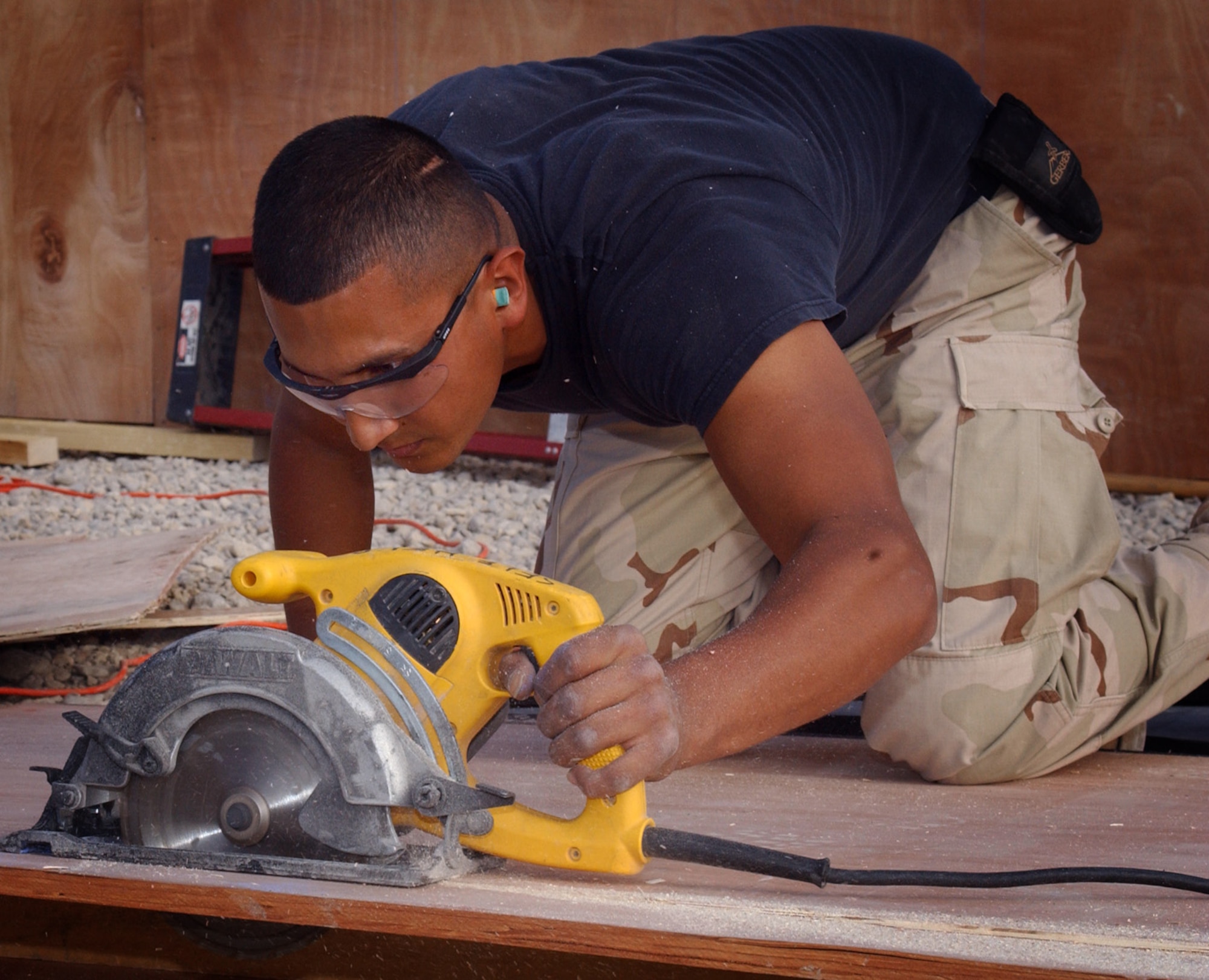 ALI BASE, Iraq (AFPN) -- The base fitness center is expanding with the addition of a separate aerobics room. Senior Airman Omar Hernandez guides a circular saw along a chalk line marked on a piece of floor sheathing. Airman Hernandez is with the 407th Expeditionary Civil Engineer Squadron (U.S. Air Force photo by Tech. Sgt. Paul Dean)
