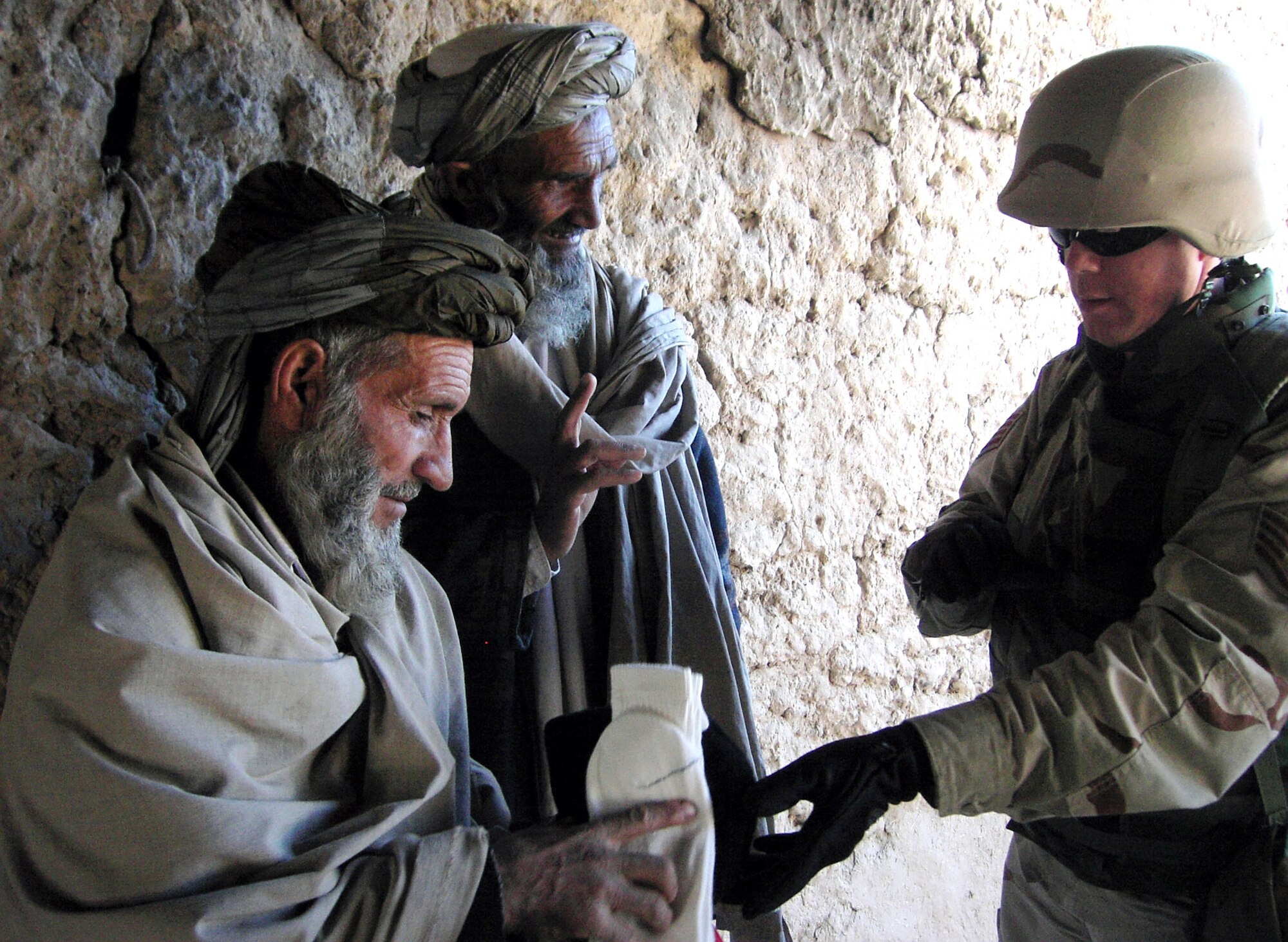 PARWAN PROVINCE, Afghanistan (AFPN) -- Staff Sgt. Ed Vaillancourt passes out socks during an Adopt-A-Village visit. Airmen from nearby Bagram Airfield distributed more than 1,000 pounds of supplies to the local village. Sergeant Vaillancourt, a native of Denmark, Maine, is deployed from Davis-Monthan Air Force Base, Ariz. (U.S. Air Force photo by Senior Airman Brad Cameron)         