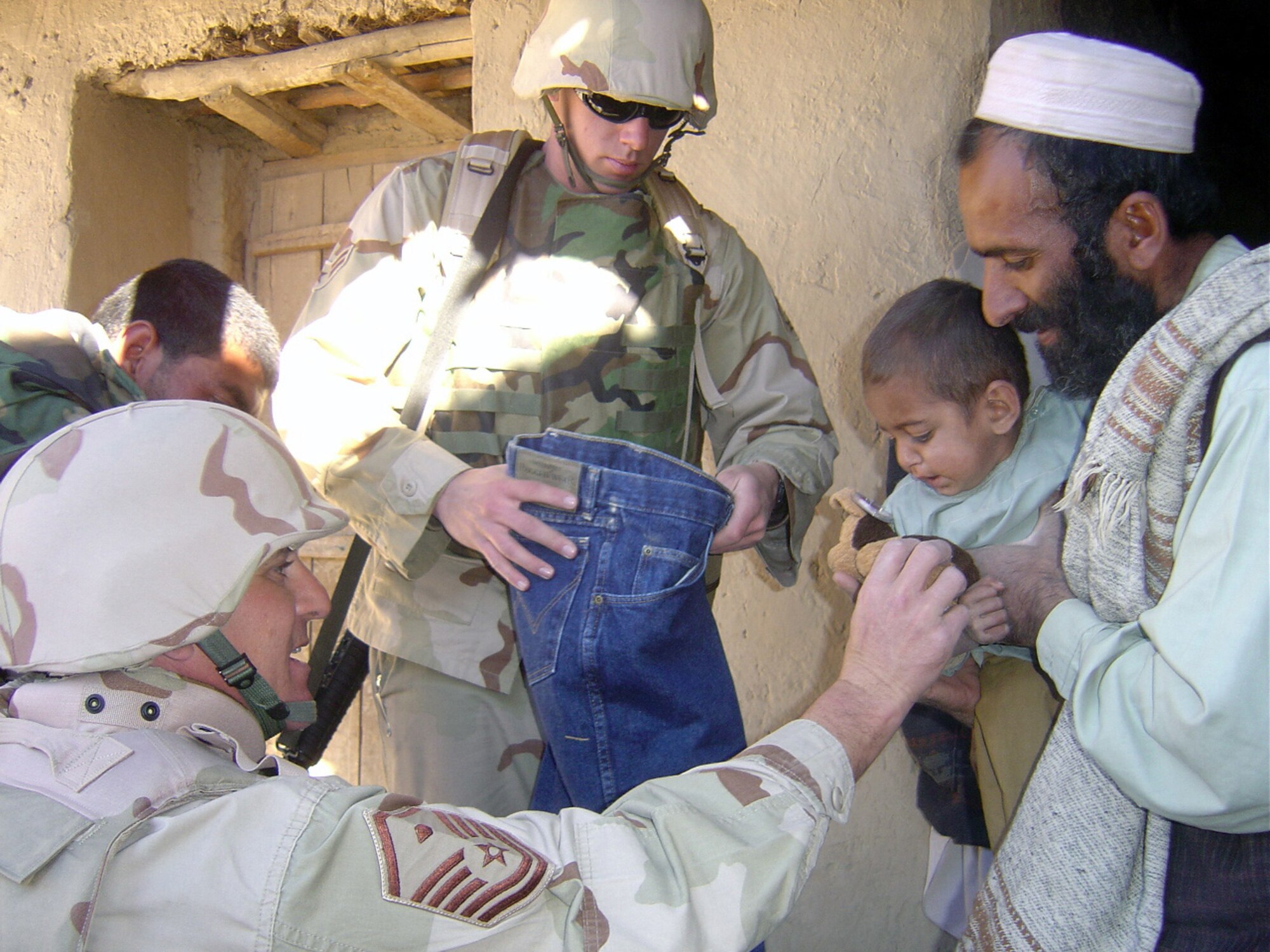 PARWAN PROVINCE, Afghanistan (AFPN) -- Master Sgt. Edgar Langdon, left, and Airman 1st Class Brian Sherman distribute clothes and toys during an Adopt-A-Village visit. Airmen from nearby Bagram Airfield distributed more than 1,000 pounds of supplies to the local village. Sergeant Langdon, a native of Hatboro, Penn., and Airman Sherman, a native of Stockton, Calif., are both deployed from Davis-Monthan Air Force Base, Ariz. (U.S. Air Force photo by Senior Airman Brad Cameron) 