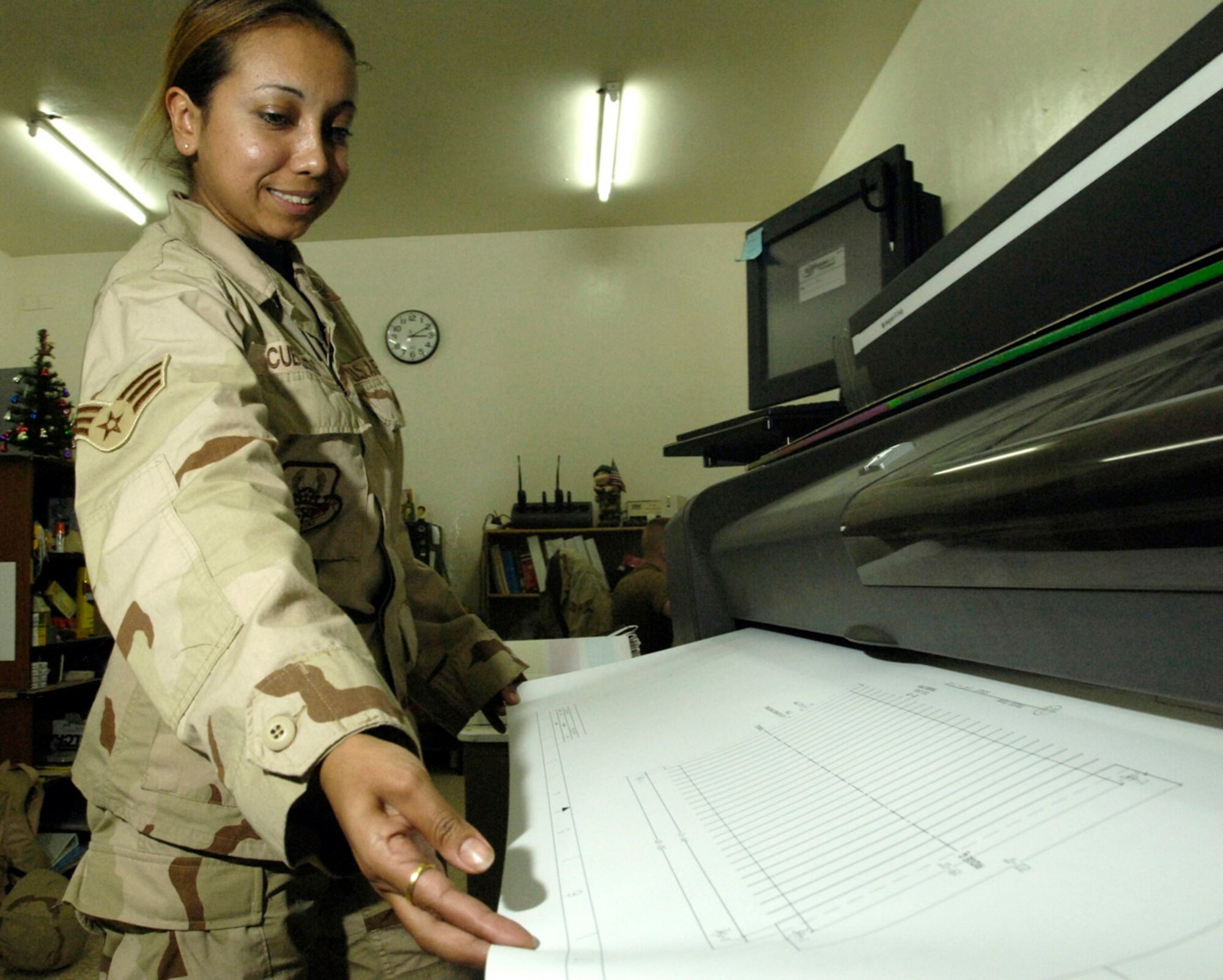 BALAD AIR BASE, Iraq (AFPN) -- Senior Airman Angelica Cubillos guides a map on a plotter as it is being printed. Airman Cubillos is with the 732nd Expeditionary Civil Engineer Squadron. (U.S. Air Force photo by Airman 1st Class Chad Watkins) 