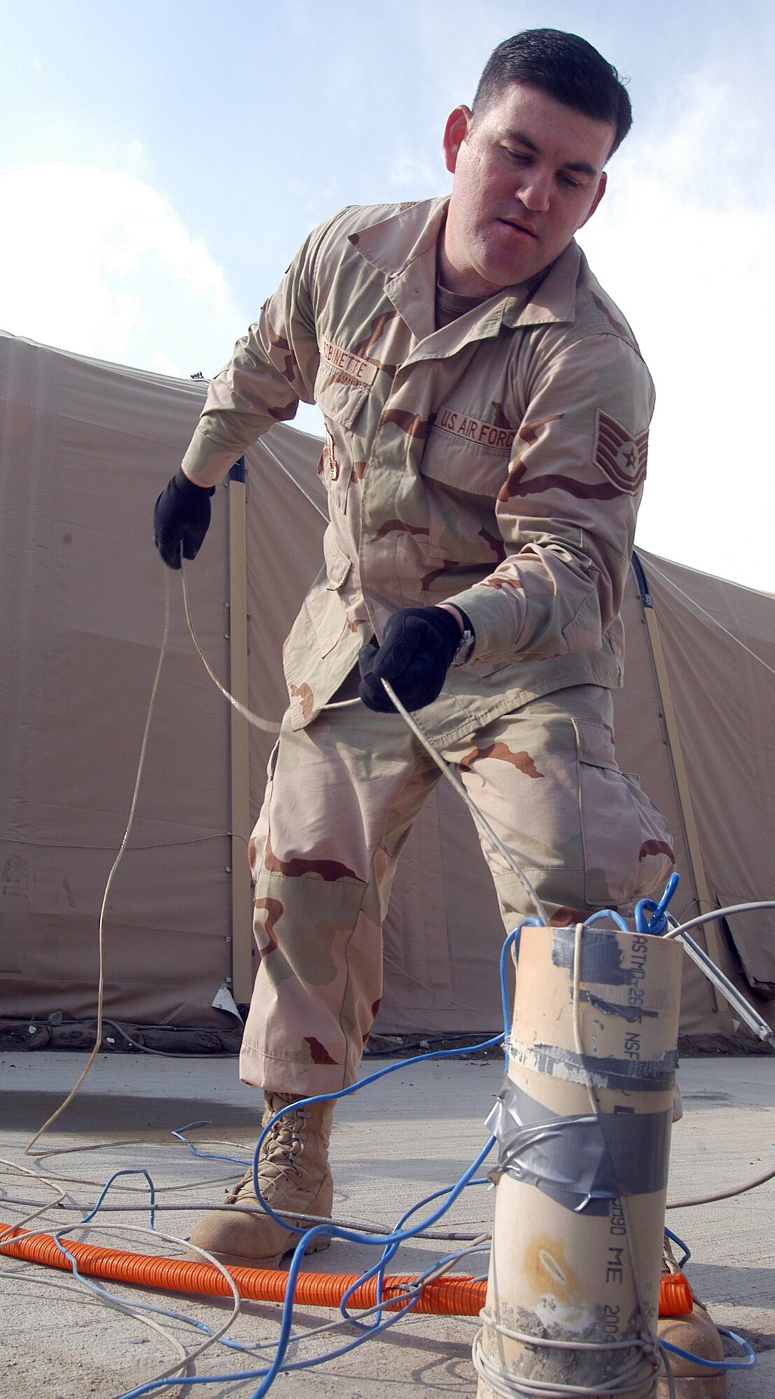 BAGRAM AIRFIELD, Afghanistan (AFPN) -- Tech. Sgt. Michael Robinette helps replace 75 yards of broken network cable. Since arriving here in September the team has re-run more than 20 network lines. Sergeant Robinette, a native of Joliet, Ill., is deployed from Davis-Monthan Air Force Base, Ariz. (U.S. Air Force photo by Staff Sgt. Marcus McDonald)                       