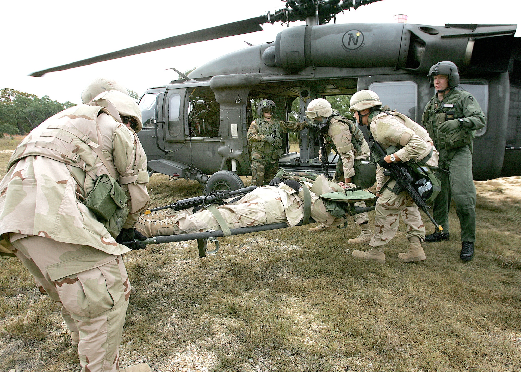 CAMP BULLIS, Texas (AFPN) -- Students of the basic combat convoy course load "casualties" on a helicopter following a simulated firefight with insurgents. The training puts students in the realistic situations they will face once in Iraq.  The students are, from left, Senior Airman Shawn Stafford, Pope Air Force Base, N.C., Airman 1st Class Gerald Scott (on stretcher), MacDill Air Force Base, Fla., Airman 1st Class Charles Davis from Elmendorf Air Force Base, Alaska, and Airman 1st Class Derick Games, Hurlburt Field, Fla. (U.S. Air Force photo by Robbin Cresswell)