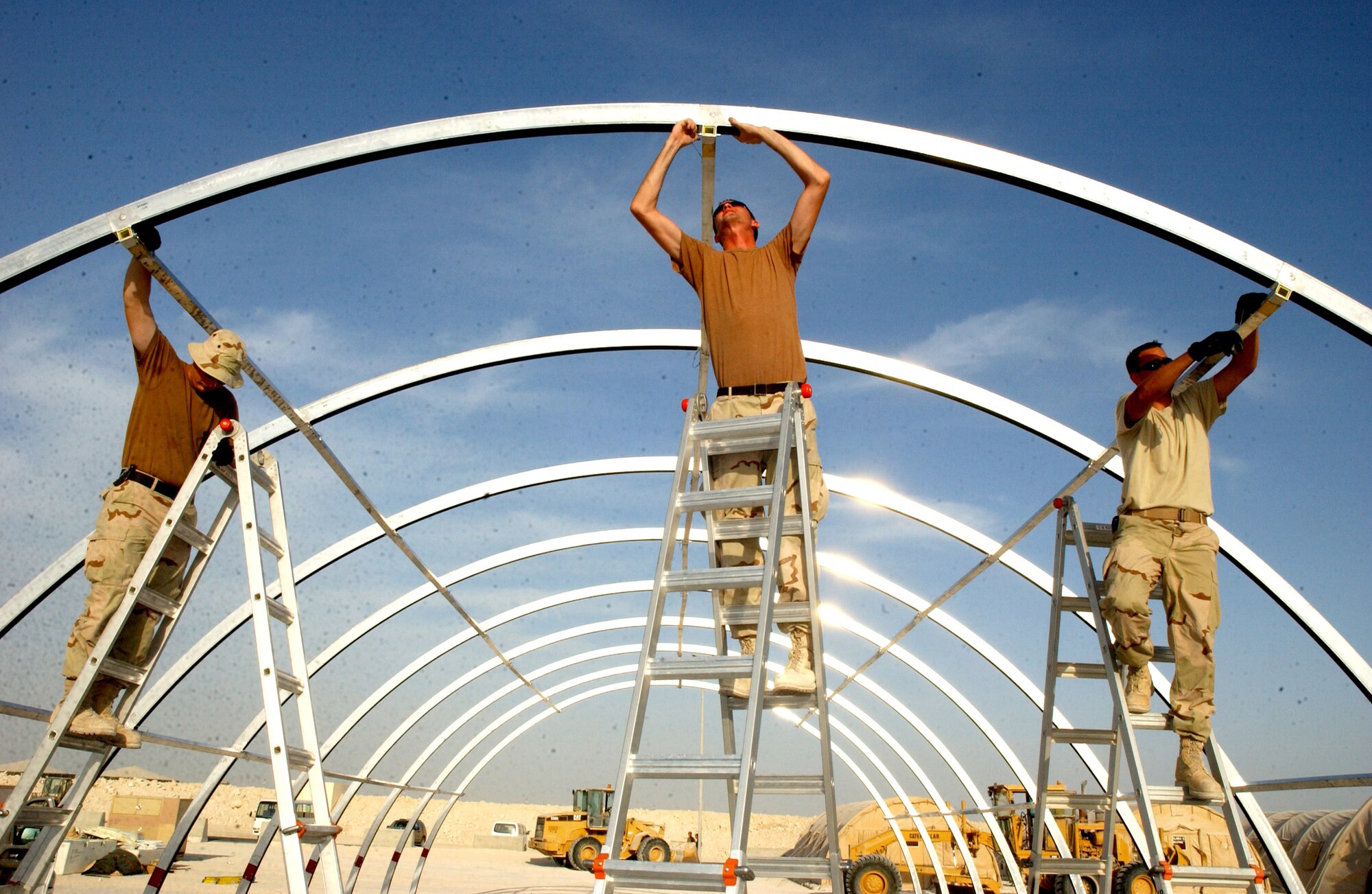 SOUTHWEST ASIA (AFPN) -- (From left) Senior Airman Aleksey Starovoytov, Airman 1st Class Ryan Watkins and Airman 1st Class Steven Kilian work to connect a frame for a shelter cover. (U.S. Air Force photo by Airman 1st Class De-Juan Haley)