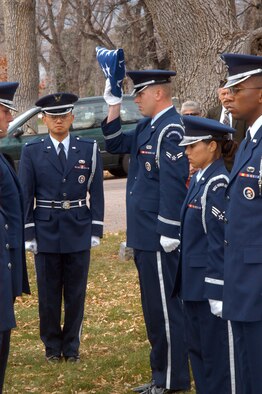 COLORADO SPRINGS, Colo. (AFPN) -- Airman 1st Class Michzel Zdenek prepares to hand a folded American flag to 1st Lt. Bruce Wang as part of a recent funeral detail. Lieutenant Wang is a member of the 1st Space Operations Squadron. Airmen Zdenek is in the 50th Civil Engineer Squadron. (U.S. Air Force photo by Staff Sgt. Don Branum)