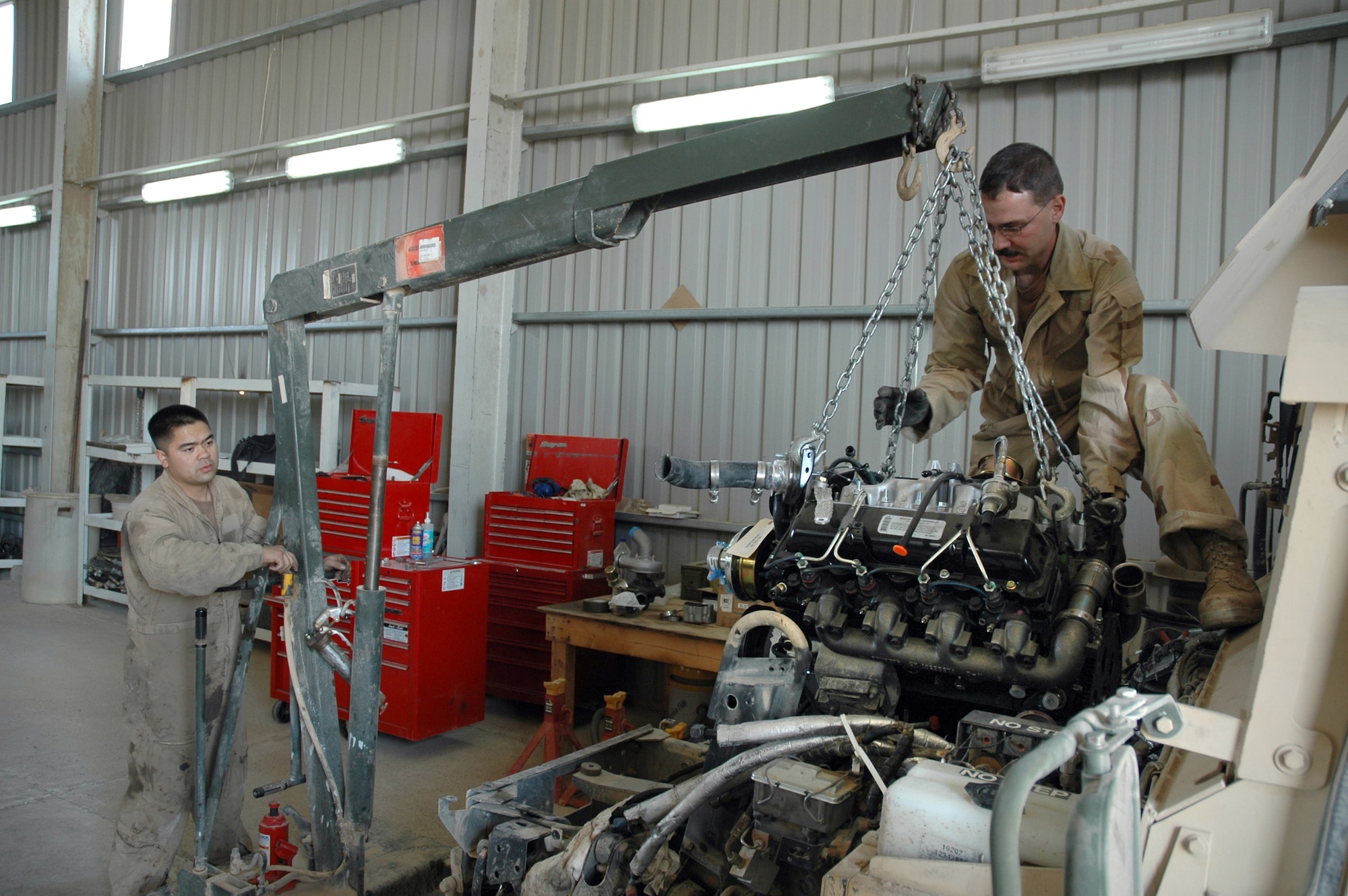 TIKRIT, Iraq (AFPN) -- Staff Sgt. Mel Perero (left) and Senior Airman Sean Johnson install a new engine in a Humvee. Mechanics assigned to the 732nd Expeditionary Logistics Readiness Squadron at base Speicher maintain armored gun trucks used by the Air Force convoy security detachment. Sergeant Perero deployed from Misawa Air Base, Japan, and Airman Johnson deployed from Vandenberg Air Force Base, Calif. (U.S. Air Force photo by Maj. Robert Couse-Baker) 