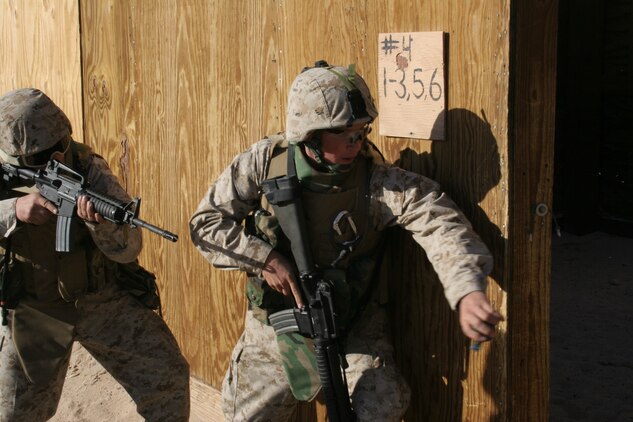 A Marine throws a dummy grenade into a room as his partner provides cover for him during a live-fire military operations in urban terrain exercise Nov. 30 at the Combat Center?s Range 111.  Both Marines are with Headquarters Company, 7th Marine Regiment, and are preparing for an upcoming deployment.