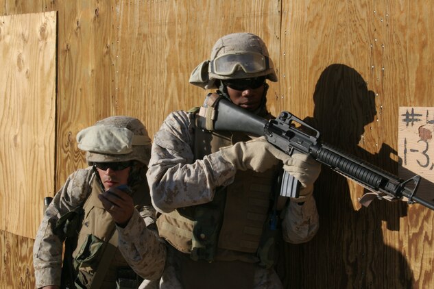 Cpl. Alfredo Moreno, a 20-year-old motor transportation driver from Azusa, Calif., shows his partner, Cpl. David Bryant Jr., motor transportation driver with Headquarters Company, 7th Marine Regiment, a dummy grenade that he is about to thrown into a room on Combat Center Range 111 military operation in urban terrain facility.