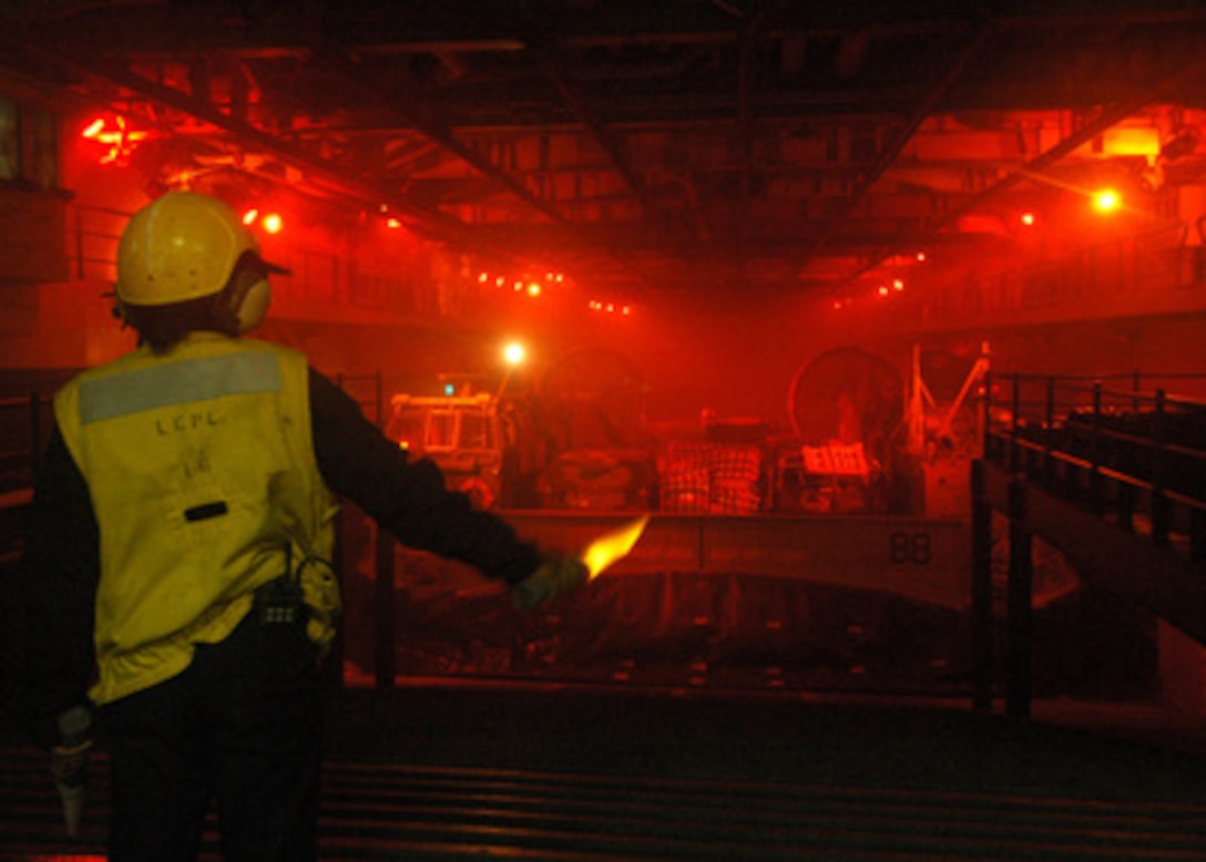 U.S. Navy Seaman Tysha Cooper signals a landing craft air cushion as it prepares to depart the well deck of the USS Iwo Jima (LHD 7) on Oct. 1, 2005. The Iwo Jima is returning to Norfolk, Va., following relief and recovery efforts as part of Joint Task Force Katrina. Department of Defense units are mobilized as part of Joint Task Force Katrina to support the Federal Emergency Management Agency's disaster-relief efforts in the Gulf Coast areas devastated by Hurricane Katrina. 