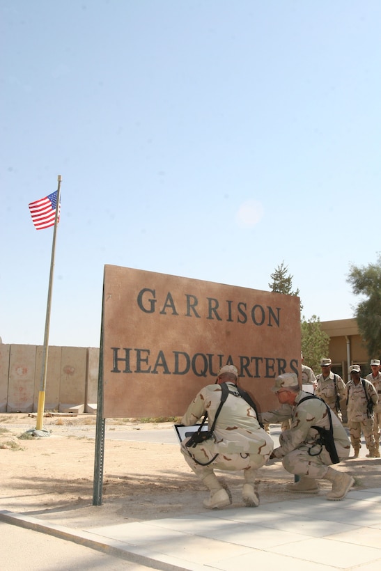 Sergeant Maj. Leon Haith, the command sergeant major for the 67th Area Support Group, and Col. Kenneth E. Hassler, commanding officer of the 67th, hang their group?s sign in front of the headquarters building, during a transfer of authority ceremony, Oct. 4, at Al Asad, Iraq.