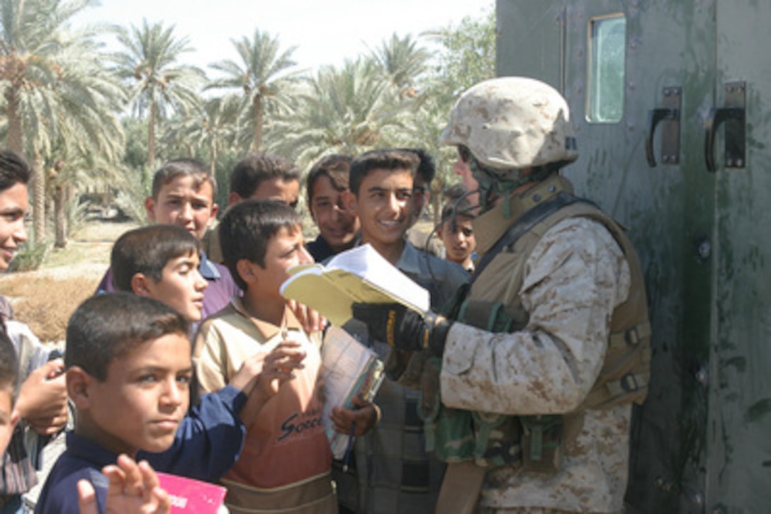 U.S. Marine Corps Cpl. Ross Casey with the 6th Civil Affairs Group attempts to communicate with local children with the assistance of an Arabic dictionary in Kharma, Iraq, on Oct. 2, 2005. 