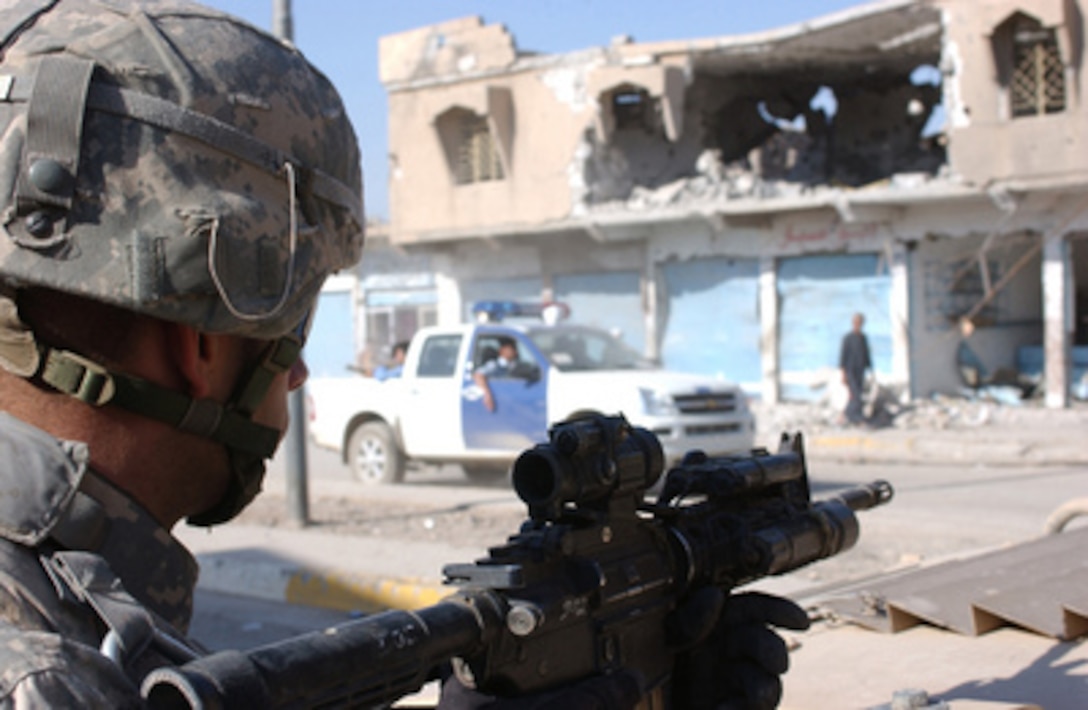 U.S. Army Pfc. Kevin L. White with Delta Company, 2nd Battalion, 325th Airborne Infantry Regiment, 82nd Airborne Division watches as vehicles carrying Iraqi police forces pass his unit's position on a street in Tall Afar, Iraq, on Oct. 3, 2005. 