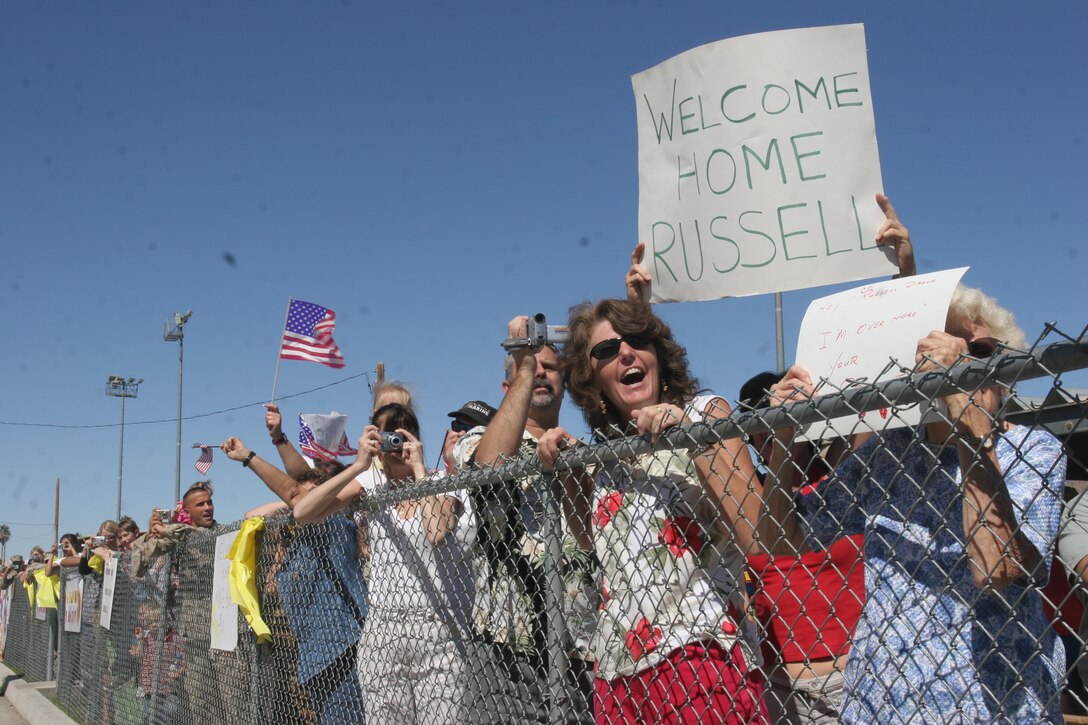 The family of Cpl. Russell S. Dasch, tank crewman, Alpha Company, 1st Tank Battalion, cheer and hold up a welcoming sign as the company arrives to Combat Center?s Victory Field during a homecoming ceremony Oct. 6.  The company was deployed to Iraq in March in support of Operation Iraq Freedom and longed for the day to return safely to their families.
