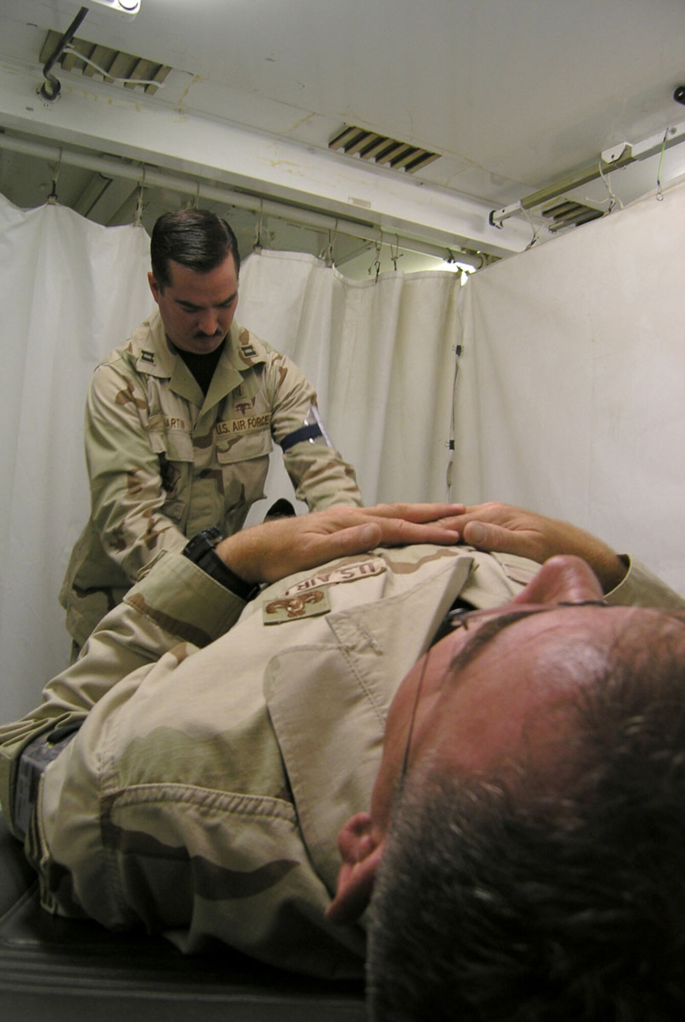 ALI BASE, Iraq -- Capt. Tony Martin evaluates a patient in the new expanded base clinic here. Captain Martin is the 777th Expeditionary Airlift Squadron medical clinic orthopedic physician assistant. (U.S. Air Force photo by Tech. Sgt. Paul Dean)
    