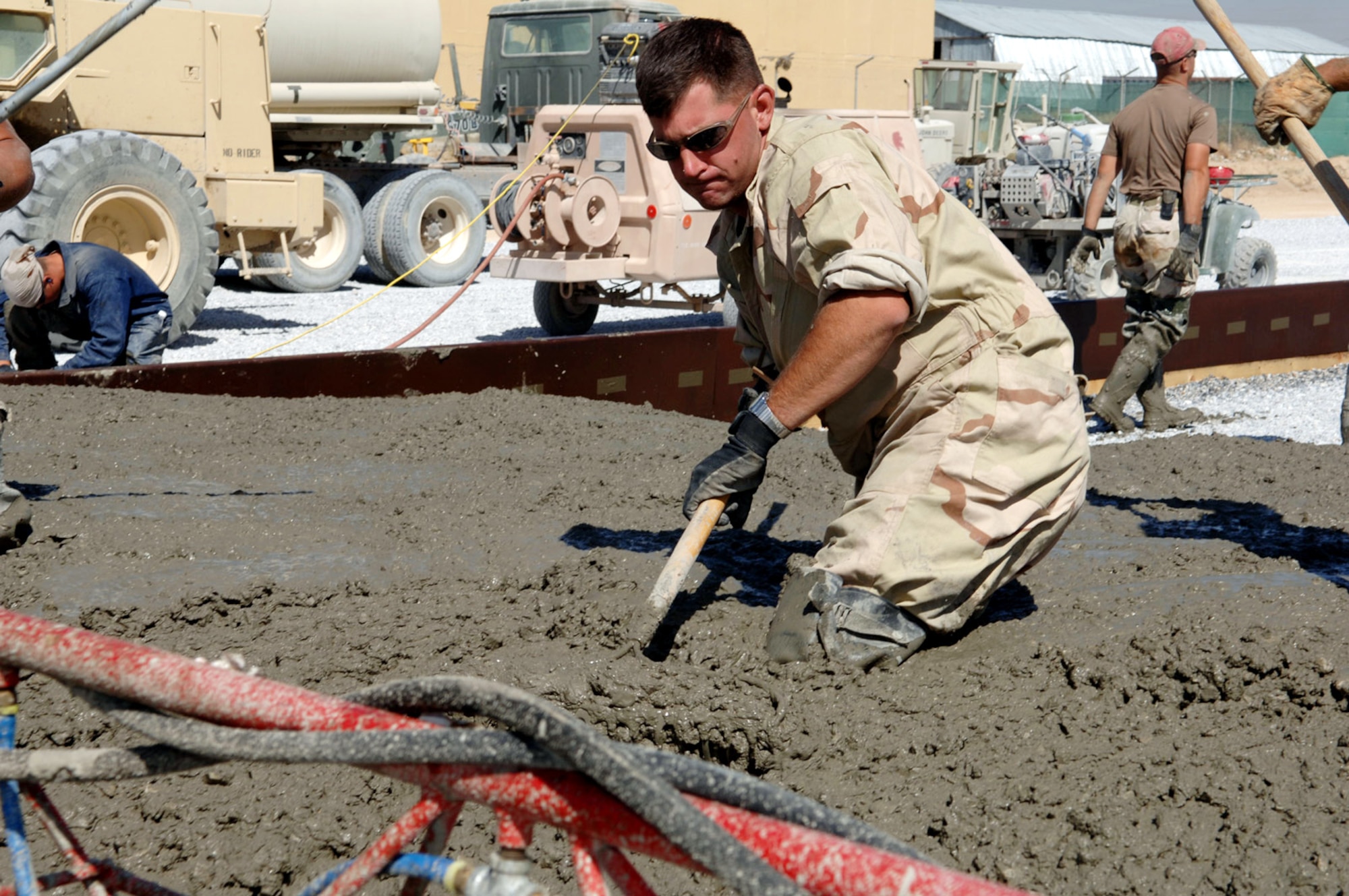 BAGRAM AIR BASE, Afghanistan -- Senior Airman Paul Lefevre spreads freshly poured concrete onto the newest section of the aircraft parking ramp here. The concrete is being used by the 1st Expeditionary Red Horse Group from Nellis Air Force Base, Nev., to add an additional 60,000 square meters of aircraft ramp space as part of a $4.4-million airfield upgrade project. Airman Lefevre is a pavement and heavy equipment operator with the 1st ERHG. (U.S. Air Force photo by Capt. James H. Cunningham) 