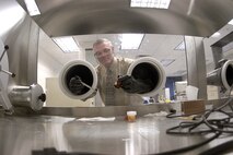 U.S. AIR FORCE ACADEMY, Colo. -- Dr. John Wilkes handles a hydrogen-reactive compound inside the vacuum chamber in the chemistry department here. The artificial compound has 10 times the storage density of liquid hydrogen and can be released in a chemical reaction to harness its energy. (U.S. Air Force photo by 2nd Lt. John Ross) 