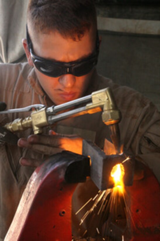 U.S. Marine Corps Lance Cpl. Nathan Harrison from Combat Logistics Battalion 8, Maintenance Company welds off the slag to screws at Camp Fallujah, Iraq, on Sept. 30, 2005. 