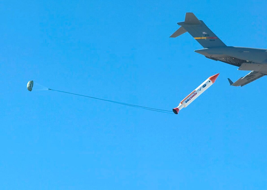 OVER EDWARDS AIR FORCE BASE, Calif. -- A 50,000-pound mock-up booster rocket deploys rolls out the back of a C-17 Globemaster III. The test was the first in a series designed to explore a more flexible and affordable satellite launch capability. (U.S. Air Force photo by Bobbi Zapka)