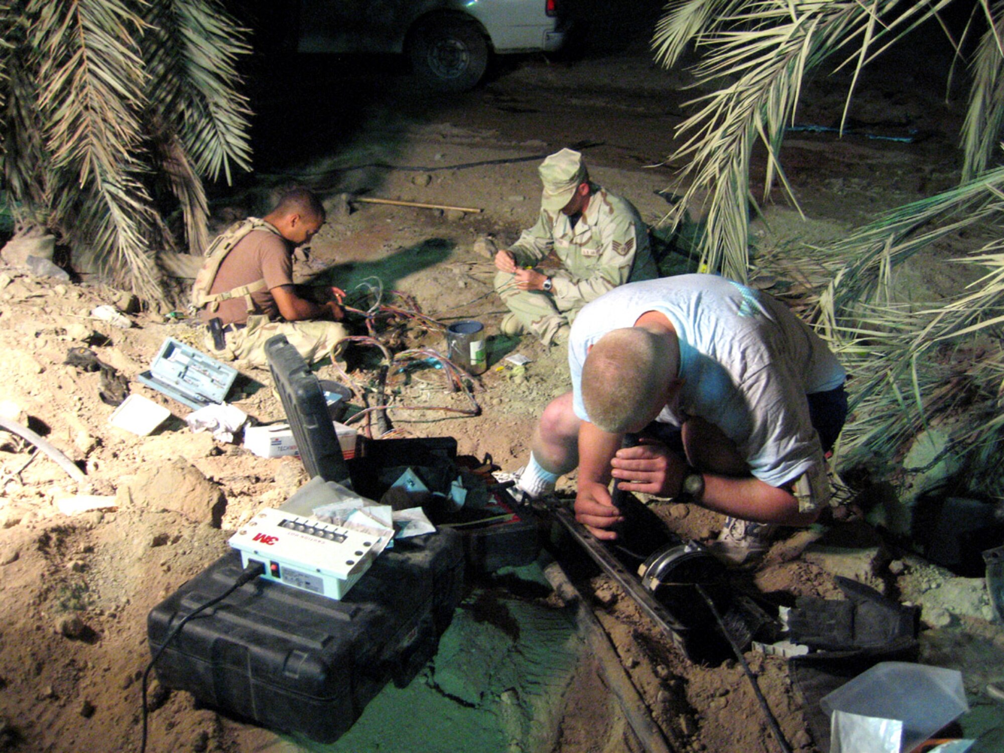 ALI BASE, Iraq -- Senior Airman Michael Woods (front) uses a fiber inspection scope to check the quality of a fiber optic connection as Staff Sgts. Fernando Perez (left) and Paul Mattke work on the copper connections.  They are assigned to the 407th Expeditionary Communications Squadron.  Airman Woods and Sergeant Perez are deployed from Lajes Field, Azores, and Sergeant Mattke is deployed from Ellsworth AFB, S.D. (U.S. Air Force photo by 1st Lt. Adam Pudenz)