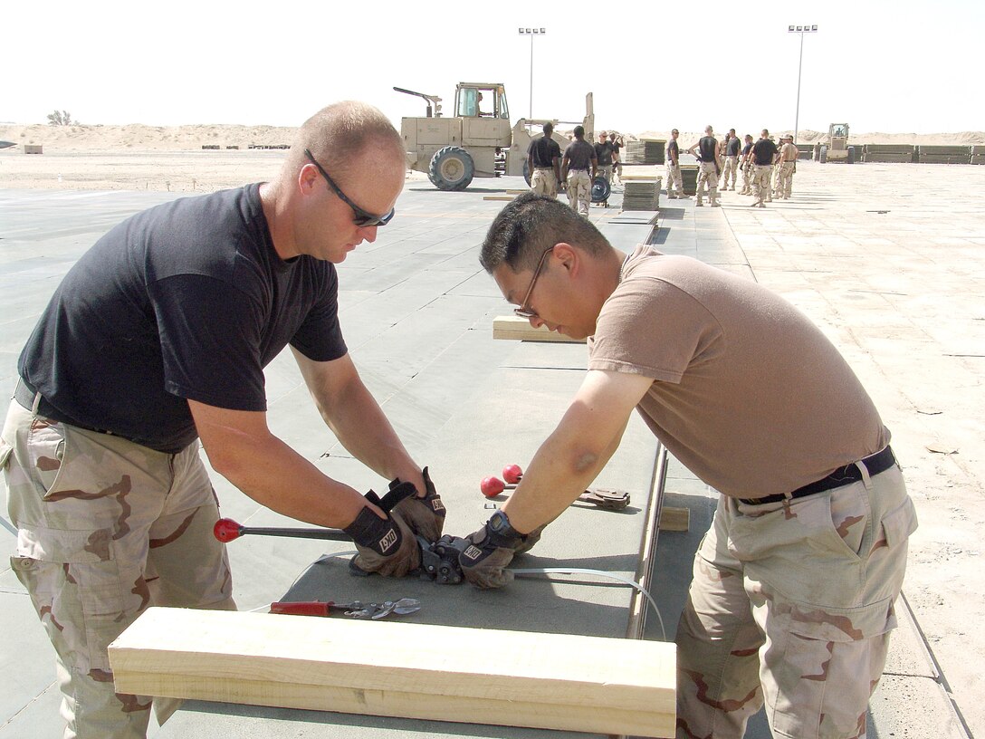 SOUTHWEST ASIA -- Staff Sgts. Aaron Wade (left) and Kenneth Pang bundle up metal planks that served as the temporary flightline surface in preparation for paving the ramp area at a forward-deployed location.  The Airmen are assigned to the 386th Expeditionary Civil Engineer Squadron and are deployed from Misawa Air Base, Japan.  (U.S. Air Force photo by Senior Airman Michael A. Garza)