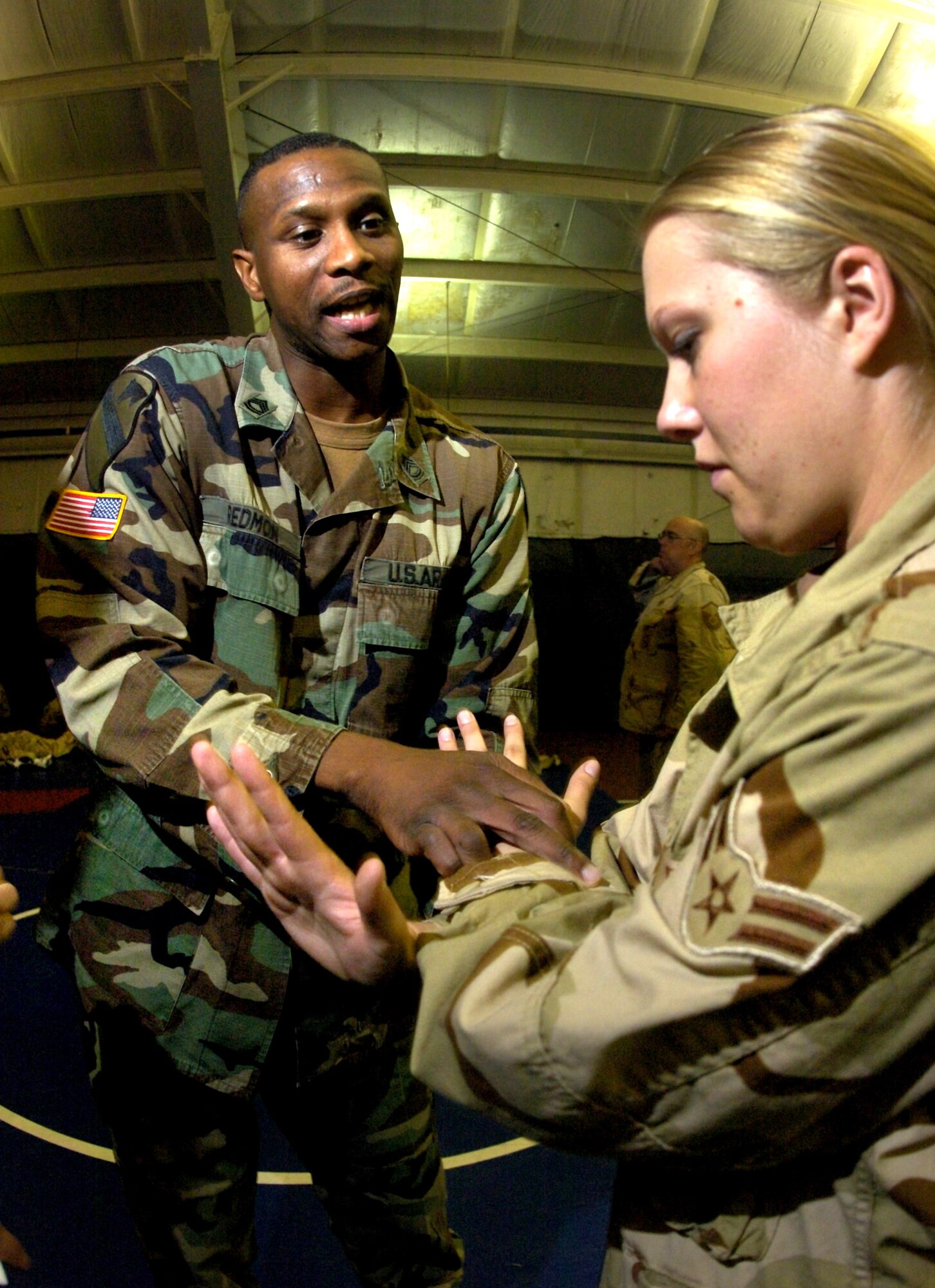 FORT LEWIS, Wash. -- Army Sgt. 1st Class John Redmon (left) shows Airman 1st Class Rachel Kindvall the proper grip and technique when defending against an upward knife attack during a detainee operations training class here.  Observer controllers like Sergeant Redmon are Soldiers with operational experience, dedicated to training servicemembers on how to safely care and control detainees with the least amount of force necessary.  Airman Kindvall is assigned to the 55th Security Forces Squadron at Offutt Air Force Base, Neb.  (U.S. Air Force photo by Tech. Sgt. Larry A. Simmons)