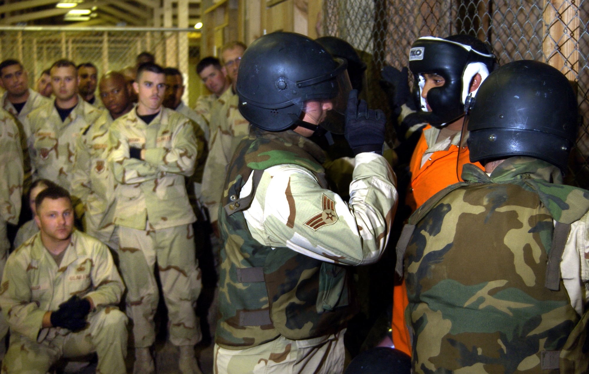 FORT LEWIS, Wash. -- Airmen watch as instructors demonstrate proper safety techniques for extracting a detainee from a cell during a detainee operations training class here.  Trainees are taught how to correctly enter and leave a cell while safely controlling either a hostile or compliant detainee.  The class teaches Airmen how to humanely care for and control detainees.  (U.S. Air Force photo by Tech. Sgt. Larry A. Simmons)