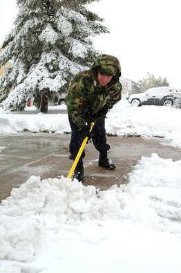 MINOT AIR FORCE BASE, N.D. -- Senior Airman Kevin O'Reilly clears his base housing driveway Oct. 5 here after the first snowfall of the year left 5 inches of snow to contend with. . Airman O'Reilly is assigned to the 5th Security Forces Squadron. (U.S. Air Force photo by Airman Christopher Boitz)