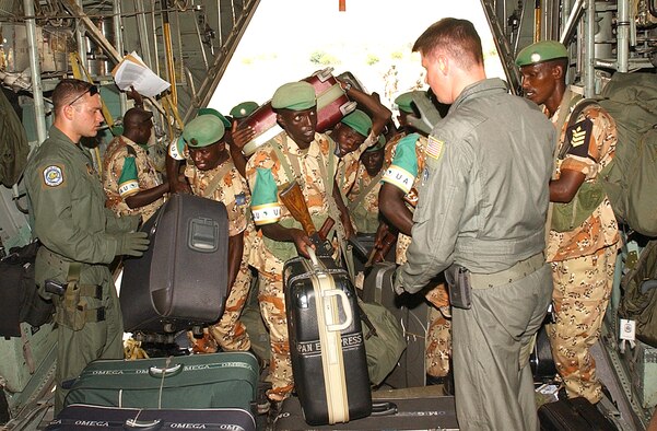 SUDAN -- Airman 1st Class Brian McCann (left) and Staff Sgt. Sean McCormick assist Rwandan peacekeepers boarding a C-130 Hercules from Ramstein Air Base, Germany, on Oct. 4.  The peacekeepers are departing the Darfur region of Sudan and returning to Rwanda after a six-month deployment supporting the African Union Missions.  The Airmen are loadmasters with the 37th Airlift Squadron at Ramstein.  (U.S. Air Force photo by Master Sgt. David D. Underwood Jr.)