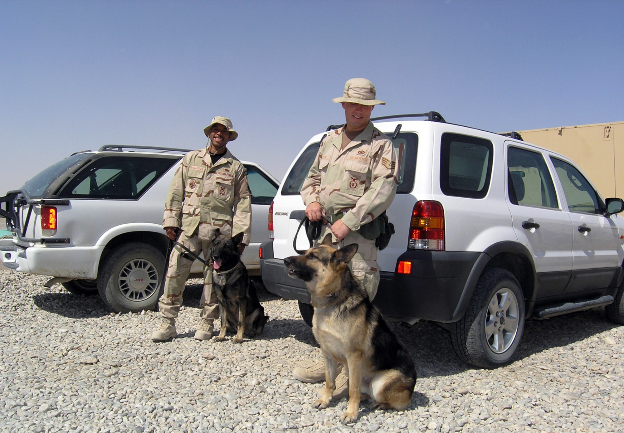 ALI BASE, Iraq -- (From left) Staff Sgt. Tyreese McAllister, Ori, Staff Sgt. Jake Bolton and Kevin wait by their vehicles here. The military working dog teams help provide full-spectrum security for deployed forces. The Airmen and their dogs are assigned to the 407th Expeditionary Security Forces Squadron. Sergeant McAllister and Ori are deployed from Langley Air Force Base, Va., and Sergeant Bolton and Kevin are deployed from Whiteman AFB, Mo.  (U.S. Air Force photo by Tech. Sgt. Paul Dean)