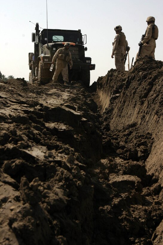 Marines assigned to Maintenance Company, Combat Logistics Battalion Eight, 2nd Force Service Support Group, stand atop the eight-foot deep rut created after removing an MK-36 wrecker weighing more than 10-tons which became mired in the mud in an area outside of Fallujah, Iraq Oct. 10. The Marines attached a cable winch from their 25-ton R-7, an Amphibious Assault Vehicle modified for recovery missions, to dislodge the wrecker. (Official Marine Corps photo by Sgt. Josh H. Hauser)(Released)