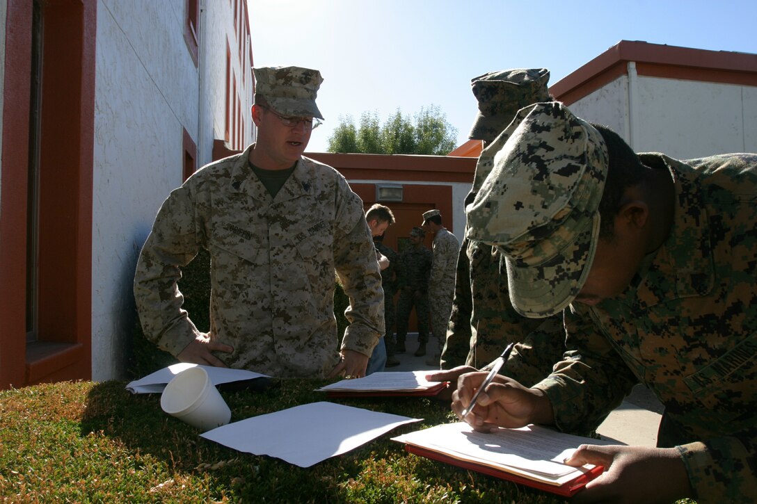 Sgt. Mikael Griffin, Career Retention Specialist for 1st Battalion, Third Marine Regiment and a native of Birmingham, Iowa, shares a moment with Cpl. Sugarray Henry, a 1/3 mortarman from Mobile, Ala., while Cpl. Michael Fiedtkou, a 1/3 mortarman from Quenns, N.Y., puts the final signature on his re-enlistment paperwork at Fort Hunter Liggett, Jolon, Calif.  Both Henry and Fiedtkou are currently serving as "aggressors" against 1/3's Distributed Operations platoon.  Griffin drove almost 500 miles to be present at the ceremony.
