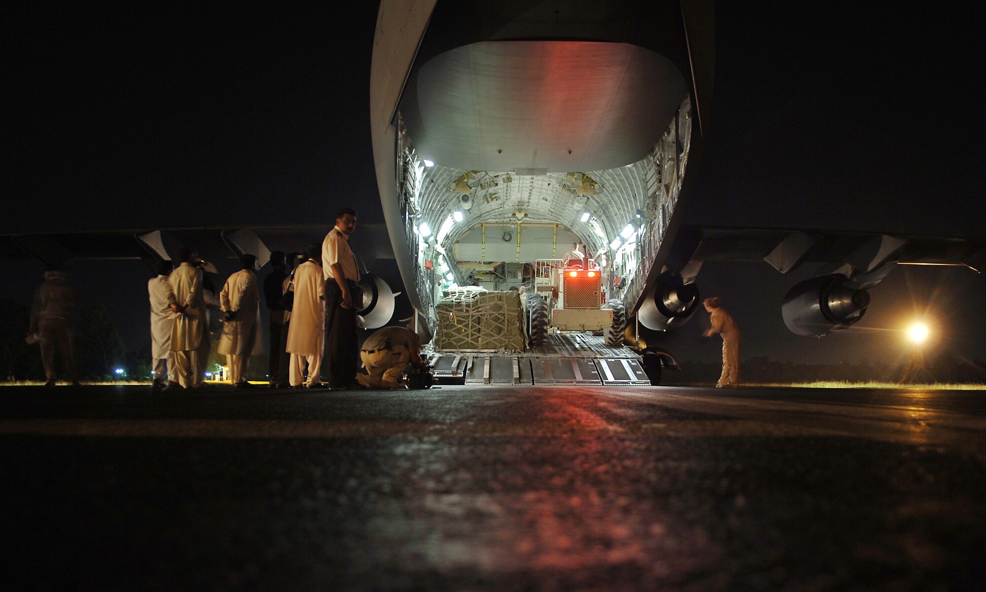 ISLAMABAD, Pakistan -- The first relief supplies from the United States are unloaded in here Oct. 9 from a C-17 Globemaster III less than 48 hours after the devastating earthquake that left thousands dead and thousands more injured. The cargo comprised 12 pallets of food, water, medicine and blankets and weighed almost 90,000 pounds. Two aerial port specialists from the 455th Expeditionary Logistics Readiness Squadron at Bagram Air Base, Afghanistan, were also on the flight to coordinate and manage cargo. The C-17 and its crew are from the 7th Airlift Squadron at McChord Air Force Base, Wash. (U.S. Air Force photo by Capt. James H. Cunningham)