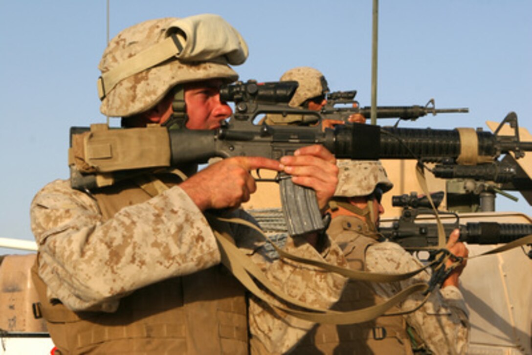 U.S. Marines sight in on a suspicious group of people congregating on a nearby rooftop while awaiting word on a suspected vehicle borne improvised explosive device along main supply route Michigan, Iraq, on Oct. 3, 2005. The Marines are assigned to Combat Logistics Battalion 8, Alpha Company. 