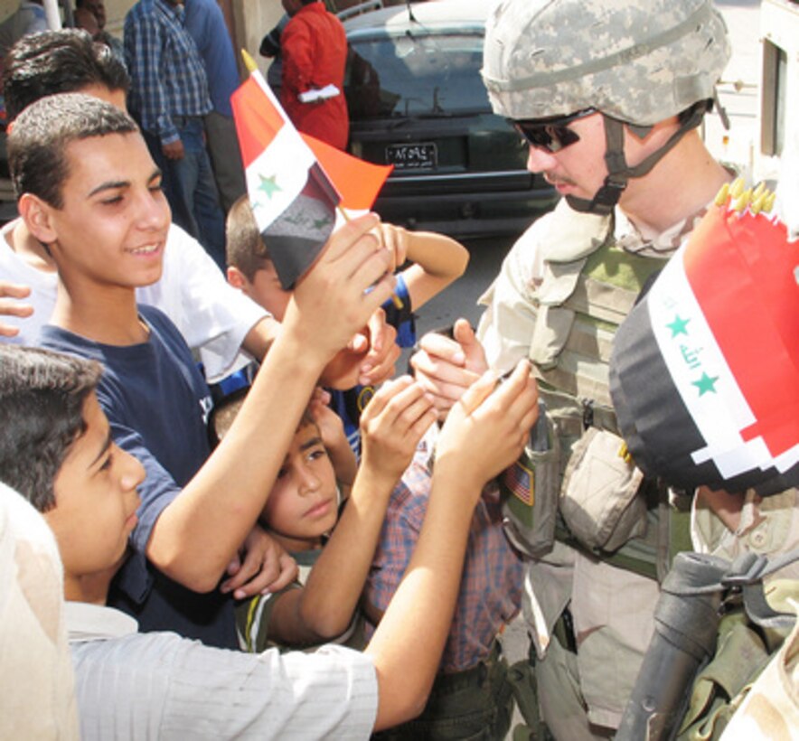 U.S. Army Sgt. Charles Hummer hands out Iraqi flags in downtown Baghdad, Iraq, as he talks to residents about their hopes and concerns on Oct. 5, 2005. 