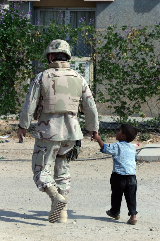 CAMP TAQADDUM, Iraq ? Army Sgt. 1st Class James L. McDonald walks with an Iraqi child here Oct. 11. 2nd Battalion, 112th Armor, 26th Infantry Division does many civil affairs missions with local schools and make relations with towns in the area of operation.  McDonald is the intelligence non-commissioned officer in charge at 2/112th and a local high school teacher in his hometown in Texas.