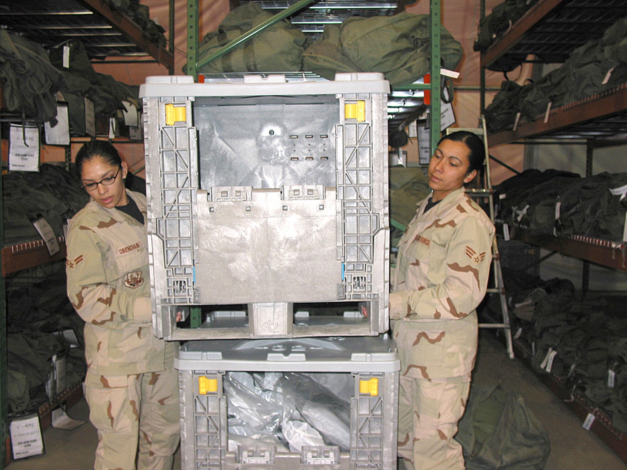 MANAS AIR BASE, Kyrgyzstan - (From left) Airman 1st Class Pamela Obenchain and Senior Airman LaTonya Jackson, 376th ELRS, set up a crate so more equipment can be sorted. The Airmen are assigned to the 376th Expesitionary Logistics Readiness Squadron. (U.S. Air Force photo)