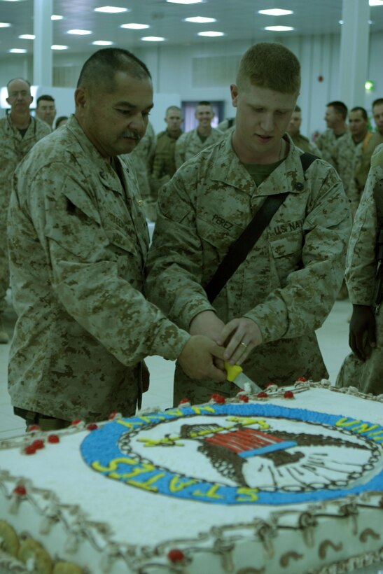 CAMP TAQADDUM, Iraq (October 13, 2005) ? Seaman Apprentice Joseph K. Perez, 19, (left) and Navy Capt. Loren J. Steenson, 56, cut the cake as oldest and youngest sailor here Oct. 13. The Marines and Sailors of 2nd Force Service Support Group (Forward) gathered to celebrate the 230th birthday of the United States Navy. Perez is a religious programs specialist, and Steenson is a dental officer, both with 2d FSSG (Fwd).