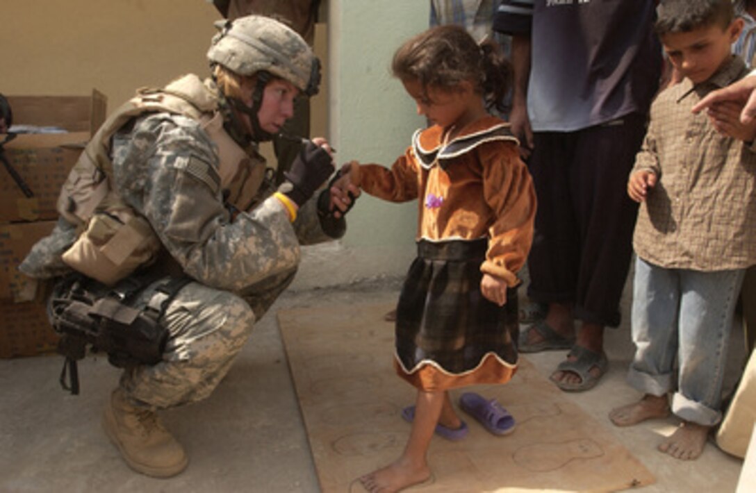 An Iraqi girl gets her feet measured for a new pair of shoes by a U.S. Army soldier at the Al Nafees primary school in Al Kafajyeh, Baghdad, Iraq, on Oct. 8, 2005. Soldiers from B Company, 448th Civil Affairs Battalion measured the children's feet and distributed the shoes. 