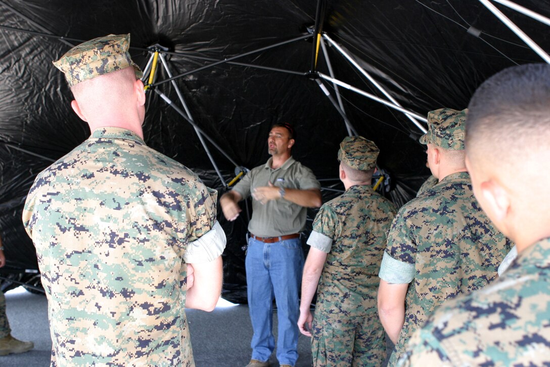 Ron Vasher, center, western region representative for Base-X Expedition Shelters, describes the inside of a Base-X shelter tent to Marines of the 15th Marine Expeditionary Unit as they learn to set up the tent at Camp Del Mar here. Marines from the 15th MEU are practicing assembling and disbanding the new tent to become more expedient during combat operations.