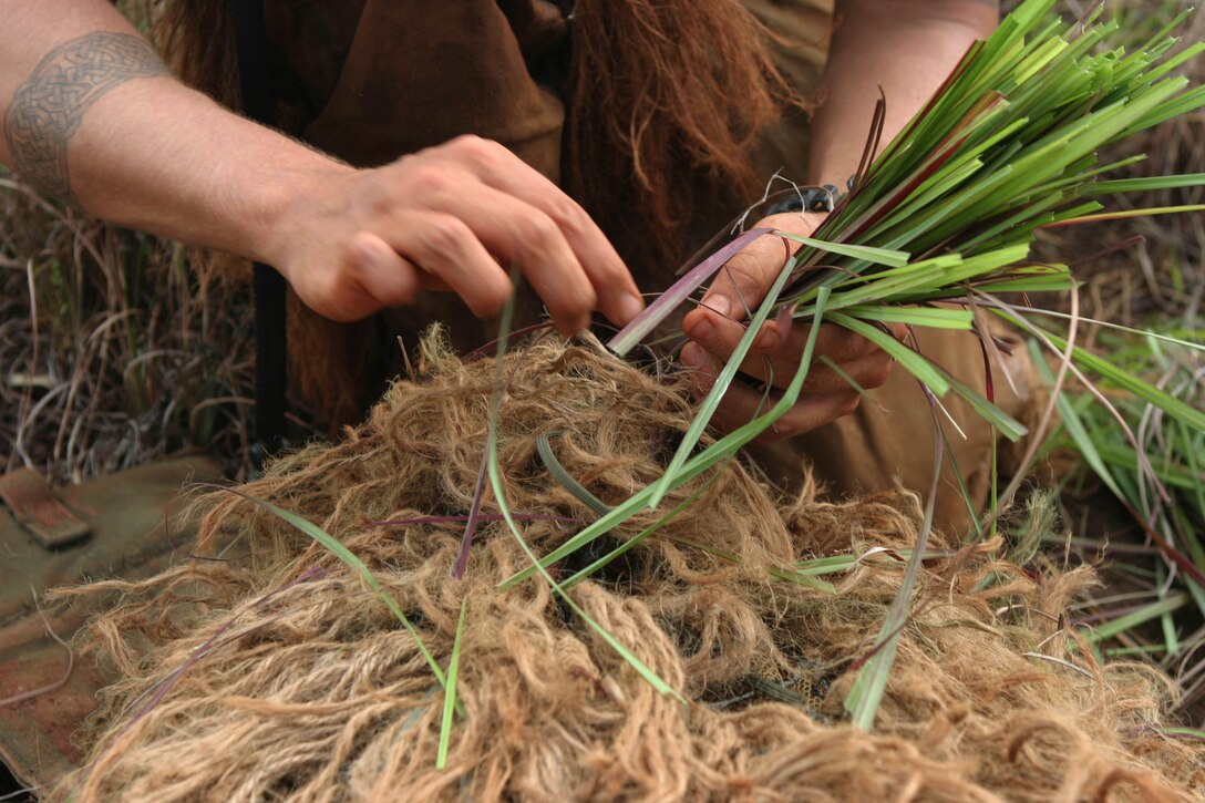 Lance Cpl. Geoff A. Kercher ties pieces of grass to his Ghillie suit in an attempt to camouflage himself during the stalking portion of the Scout Sniper Basic Course at Schofield Barracks' East Range Training Area, Oct. 13. Students attach what they can to their Ghillie suit in order to blend in with their surroundings as they stalk their target, hopefully, unnoticed.