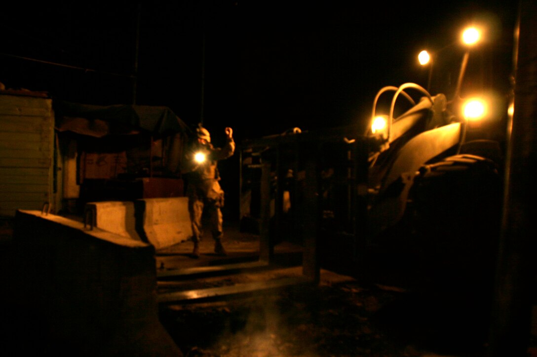 FALLUJAH, Iraq -- A Marine assigned to Transportation Company, Combat Logistics Battalion 8, 2nd Force Service Support Group (Forward), helps position a concrete barrier in preparation for Iraq’s Oct. 15 vote on their constitutional referendum. The Marines worked under the cover of darkness in order to help provide secure polling sites for tomorrow’s voters in the city of Fullujah. (Official Marine Corps photo by Sgt. Josh H. Hauser)(Released)