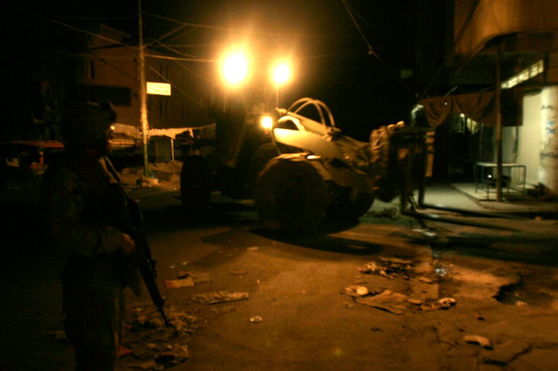FALLUJAH, Iraq --A Marine assigned to Transportation Company, Combat Logistics Battalion 8, 2nd Force Service Support Group (Forward), provides security while a forklift positions a concrete barrier in preparation for Iraq’s Oct. 15 vote on their constitutional referendum. The Marines worked under the cover of darkness in order to help provide secure polling sites for tomorrow’s voters in the city of Fullujah. (Official Marine Corps photo by Sgt. Josh H. Hauser)(Released)