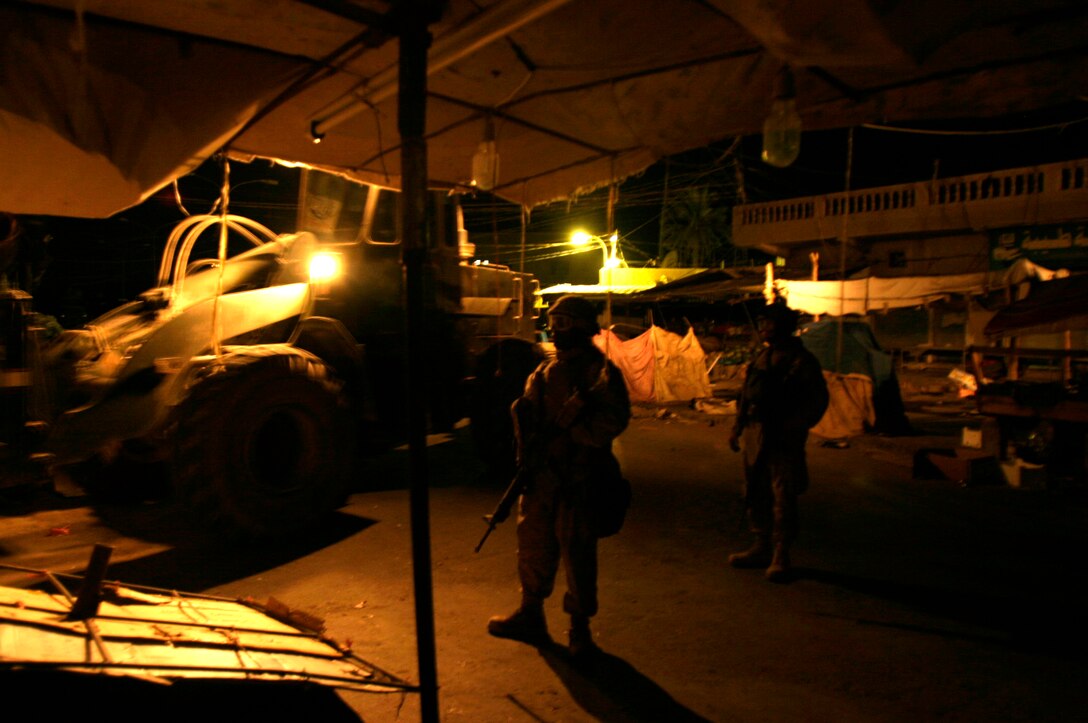 FALLUJAH, Iraq -- Marines assigned to Transportation Company, Combat Logistics Battalion 8, 2nd Force Service Support Group (Forward), provide security while a forklift positions a concrete barrier in preparation for Iraq’s Oct. 15 vote on their constitutional referendum. The Marines worked under the cover of darkness in order to help provide secure polling sites for tomorrow’s voters in the city of Fullujah. (Official Marine Corps photo by Sgt. Josh H. Hauser)(Released)