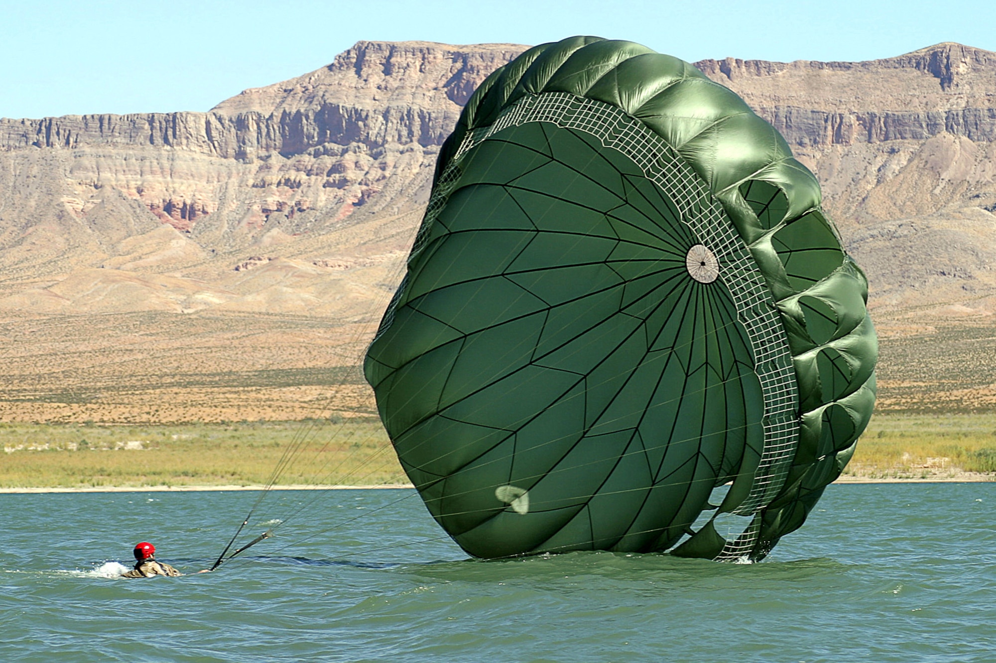 NELLIS AIR FORCE BASE, Nev. -- Senior Airman Christopher Harding gathers his parachute after landing in Lake Mead. A pararescueman with the 55th Rescue Squadron here, he had just jumped out of a C-130 Hercules as part of a rescue and recovery exercise. The squadron has 16 pararescueman who were involved in recovery missions during Hurricane Katrina and Rita. (U.S. Air Force photo by Julie Ray)