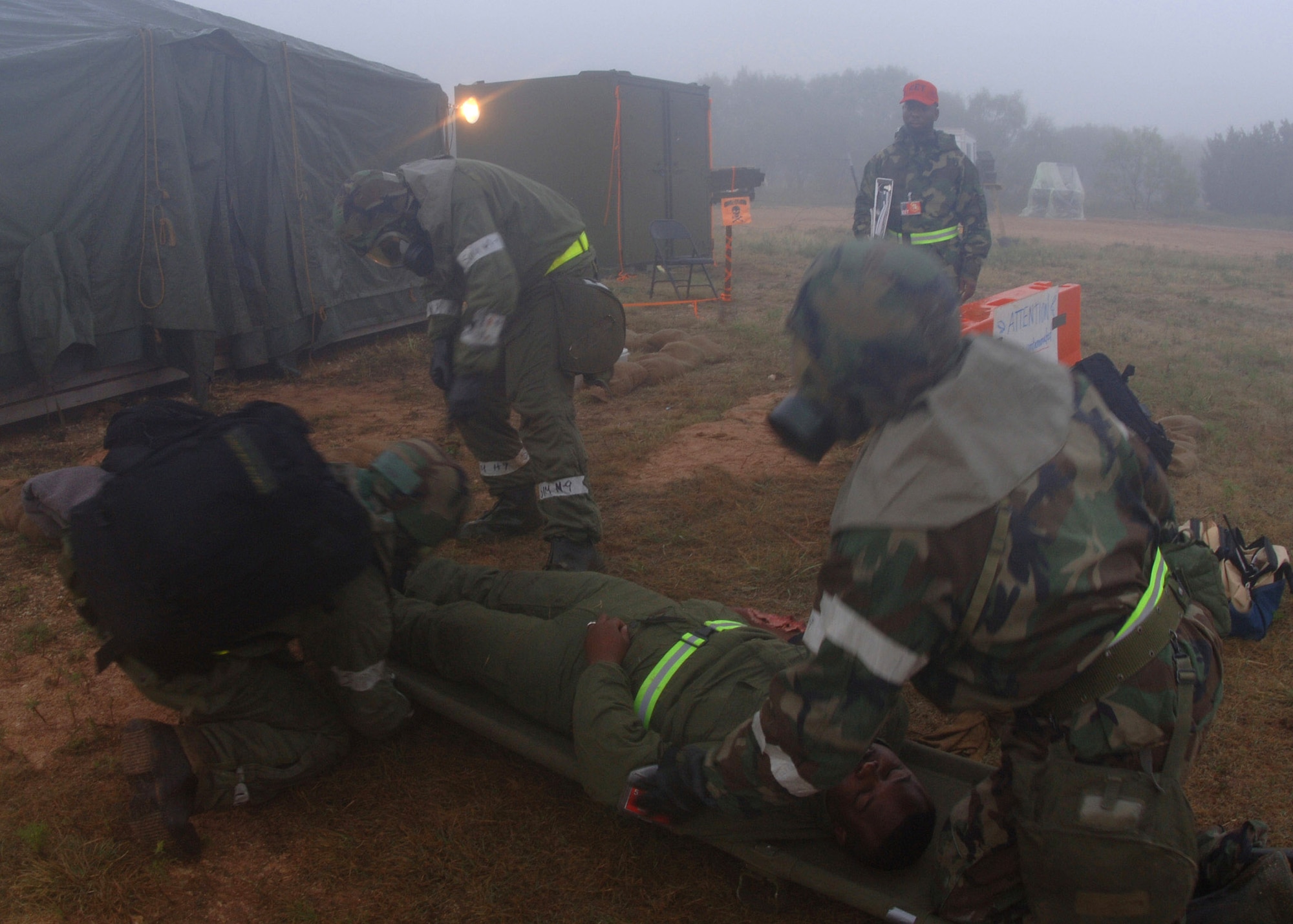DYESS AIR FORCE BASE, Texas -- An exercise evaluation team member evaluates, from left to right, Airman 1st Class Aaron Oeth, Senior Airman Micah Thornton, Staff Sgt. Roderick Jones as they strap a moulage victim onto a litter. The Airmen are assigned to the 7th Services Squadron. (U.S. Air Force photo by Staff Sgt. Araceli Alarcon)   