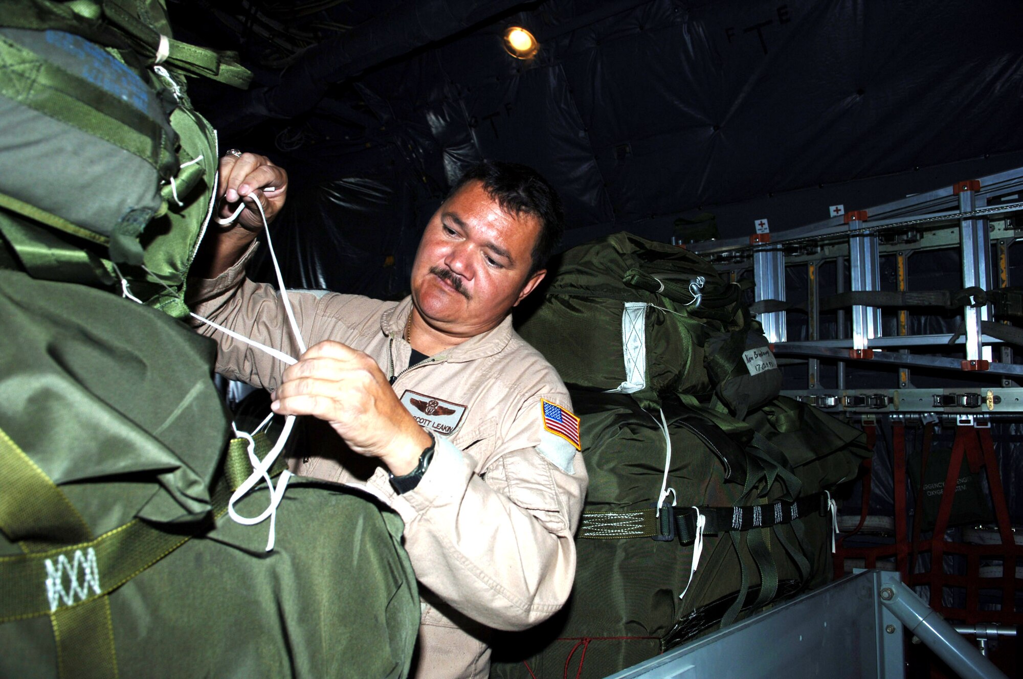 BAGRAM AIR BASE, Afghanistan -- Master Sgt. Scott L. Leakin attaches a parachute to relief supplies destined for Pakistan. A loadmaster with the 517th Airlift Squadron, his C-130 air dropped 14 pallets of supplies into the country, devastated by an Oct. 8 by a magnitude 7.6 earthquake. It was the Air Force's first such airdrop. Soldiers and Airmen here assemble approximately 20,000 pounds of food, blankets, and supplies for the drop. To date, more than 180,000 pounds of food, water, cots and medical supplies have been flown out of Bagram headed for Pakistan. Master Sgt. Leakin is deployed here from Elmendorf Air Force Base, Alaska. (U.S. Air Force photo by Capt. James H. Cunningham)
