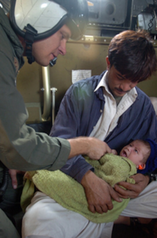U.S. Navy Petty Officer 2nd Class John Wilkins comforts a Pakistani baby aboard a Navy MH-53 Sea Dragon helicopter en route from Muzafarabad to Chaklala, Pakistan, for medical treatment on Oct. 14, 2005. The Navy helicopter crew delivered relief supplies to Muzafarabad and is airlifting the injured out. The Department of Defense is supporting the State Department by providing disaster relief supplies and services following the massive earthquake that struck Pakistan and parts of India and Afghanistan. Wilkins is an aviation electronics technician attached to Helicopter Mine Countermeasure Squadron 15 of Naval Air Station Norfolk, Va. 