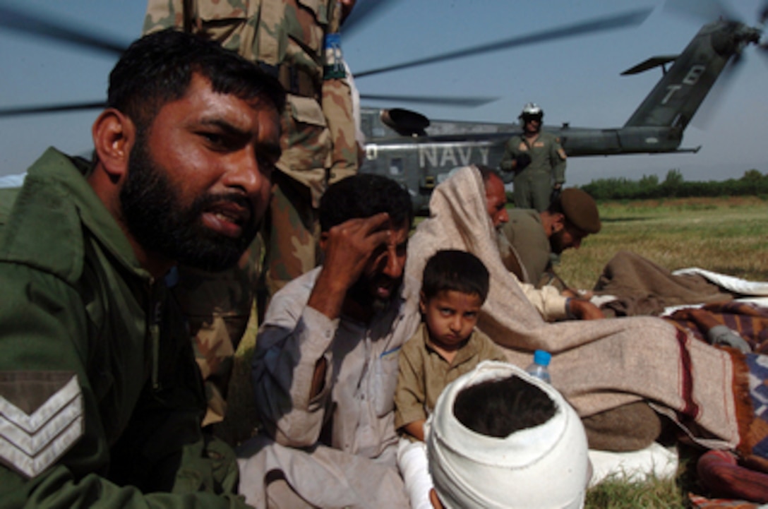 A Pakistani soldier comforts civilians after they were transported aboard a U.S. Navy MH-53 Sea Dragon helicopter for medical treatment in Chaklala, Pakistan, on Oct. 14, 2005. The Navy helicopter crew delivered relief supplies to Muzafarabad, Pakistan, then airlifted the injured out. The Department of Defense is supporting the State Department by providing disaster relief supplies and services following the massive earthquake that struck Pakistan and parts of India and Afghanistan. The Sea Dragon and its crew are attached to Helicopter Mine Countermeasure Squadron 15 of Naval Air Station Norfolk, Va. 