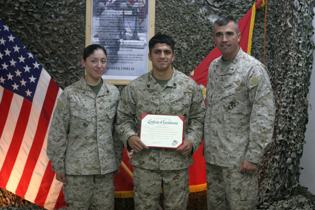 CAMP TAQADDUM, Iraq (Oct. 16, 2005) – Sergeant Ashley J. Zoza (center), an air traffic control communications technician with Marine Air Control Squadron 2, 2nd Marine Aircraft Wing, poses for a photo with his wife, Cpl. Ruth C. Zoza, a meteorology and oceanography annalist (left), and Brigadier Gen. John E. Wissler, commanding genereal, 2nd Force Service Support Group (Forward), after reenlisting in the United States Marine Corps during a ceremony here Oct. 15. Zoza, a Van Buren, Ark., native, deployed to Iraq in July as part of Operation Iraqi Freedom. (Photo by Cpl. John E. Lawson Jr.)